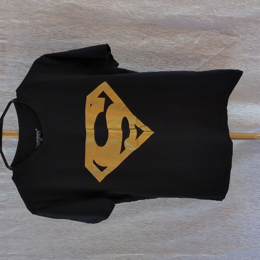 black t-shirt featuring a shiny gold Superman logo graphic. 